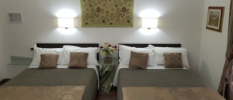 Habitación de hotel con dos camas individuales, cada una con cubrecama y almohadas verdes a juego. Entre las camas, una pequeña mesa con un florero.