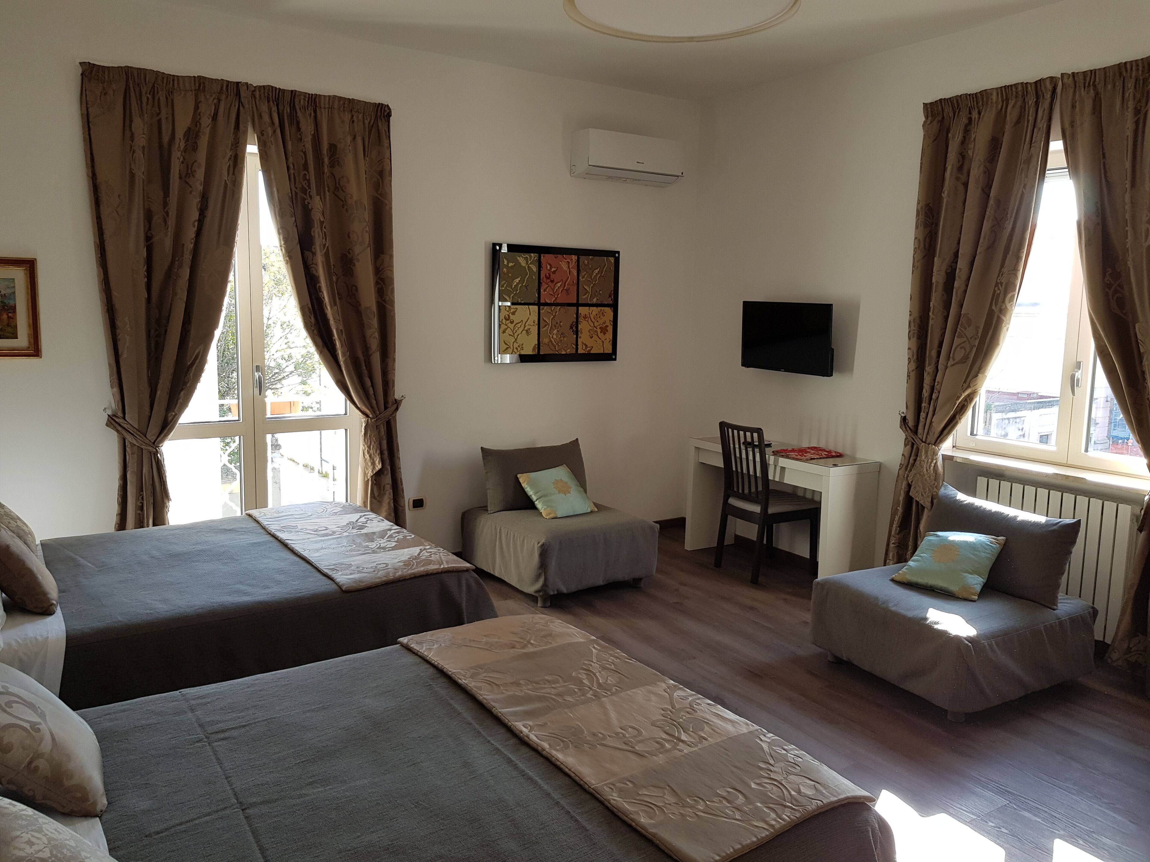Una habitación con dos camas, un escritorio, una silla y un televisor.