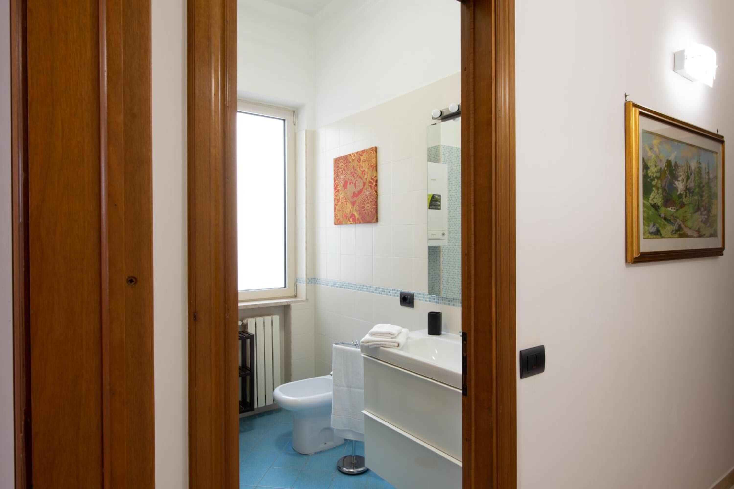 A bathroom with a toilet, sink, and a window.