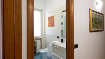 A bathroom with a toilet, sink, and a window.