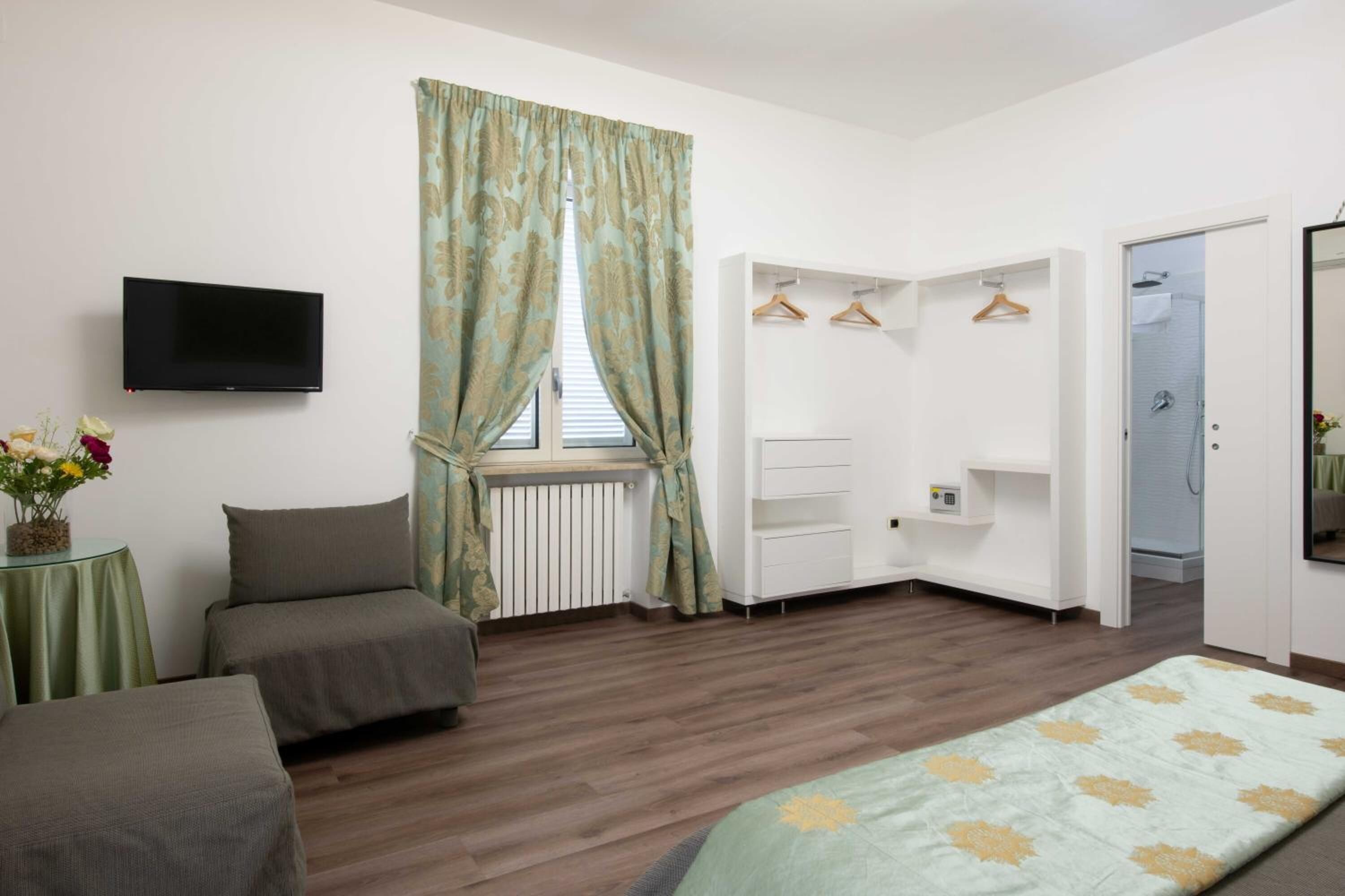 Une chambre à coucher avec un lit, une télévision, une armoire et un radiateur.