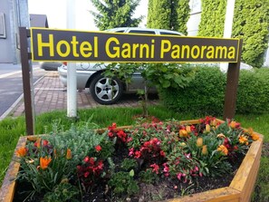 Une enseigne pour l’hôtel Garni Panorama, avec un parterre de fleurs devant.