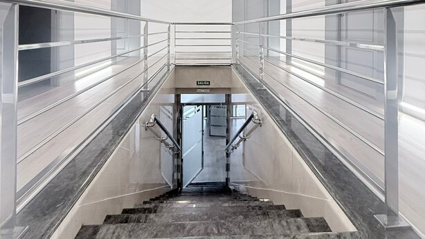 Ein modernes Interieur mit Glasdecke, einer zentralen Treppe und einem Schild mit der Aufschrift 'SALIDA'.