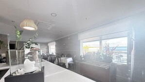 Eine moderne Küche mit einer langen Arbeitsplatte, einer Pendelleuchte und Blick ins Freie durch große Fenster.