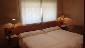 Ein Hotelzimmer mit einem großen Bett, zwei Nachttischen, einer Lampe und einem Fenster mit Vorhängen.