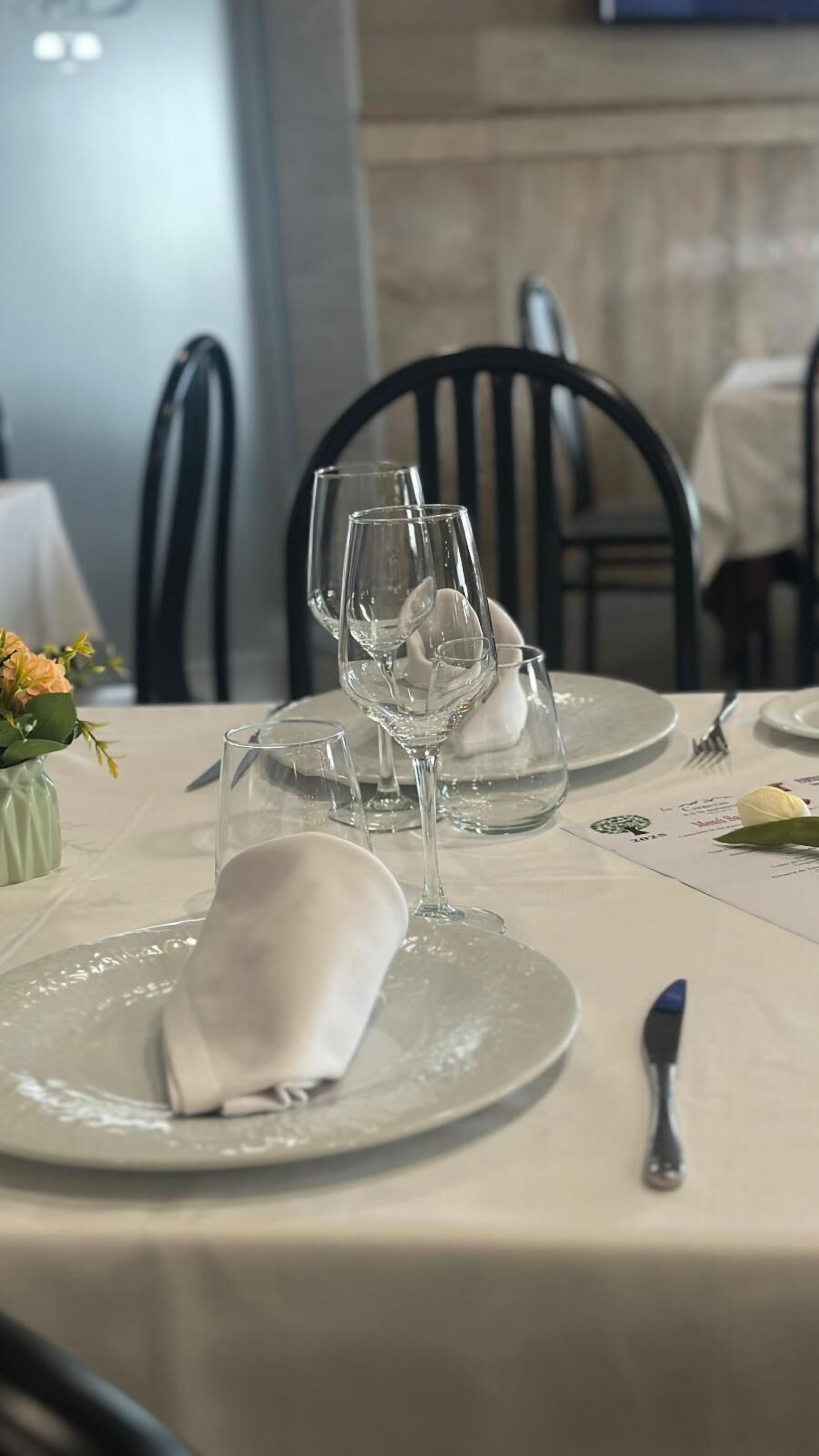 Una mesa de comedor dispuesta con platos, vasos y un tenedor.