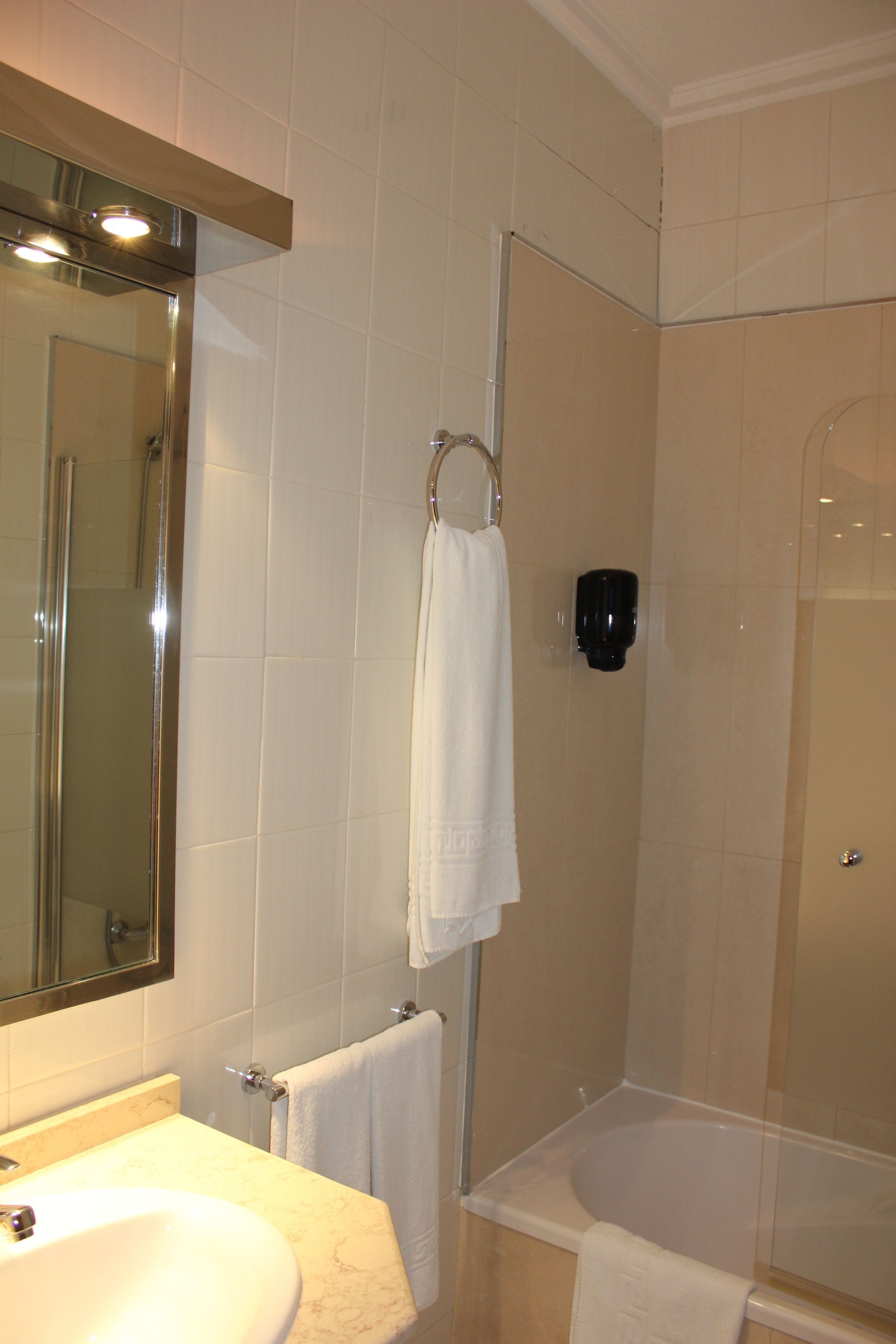Un baño con lavabo, espejo, toallero y zona de ducha.