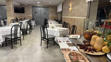 Un espace repas comprenant plusieurs tables, des chaises et un long panneau présentant le menu.