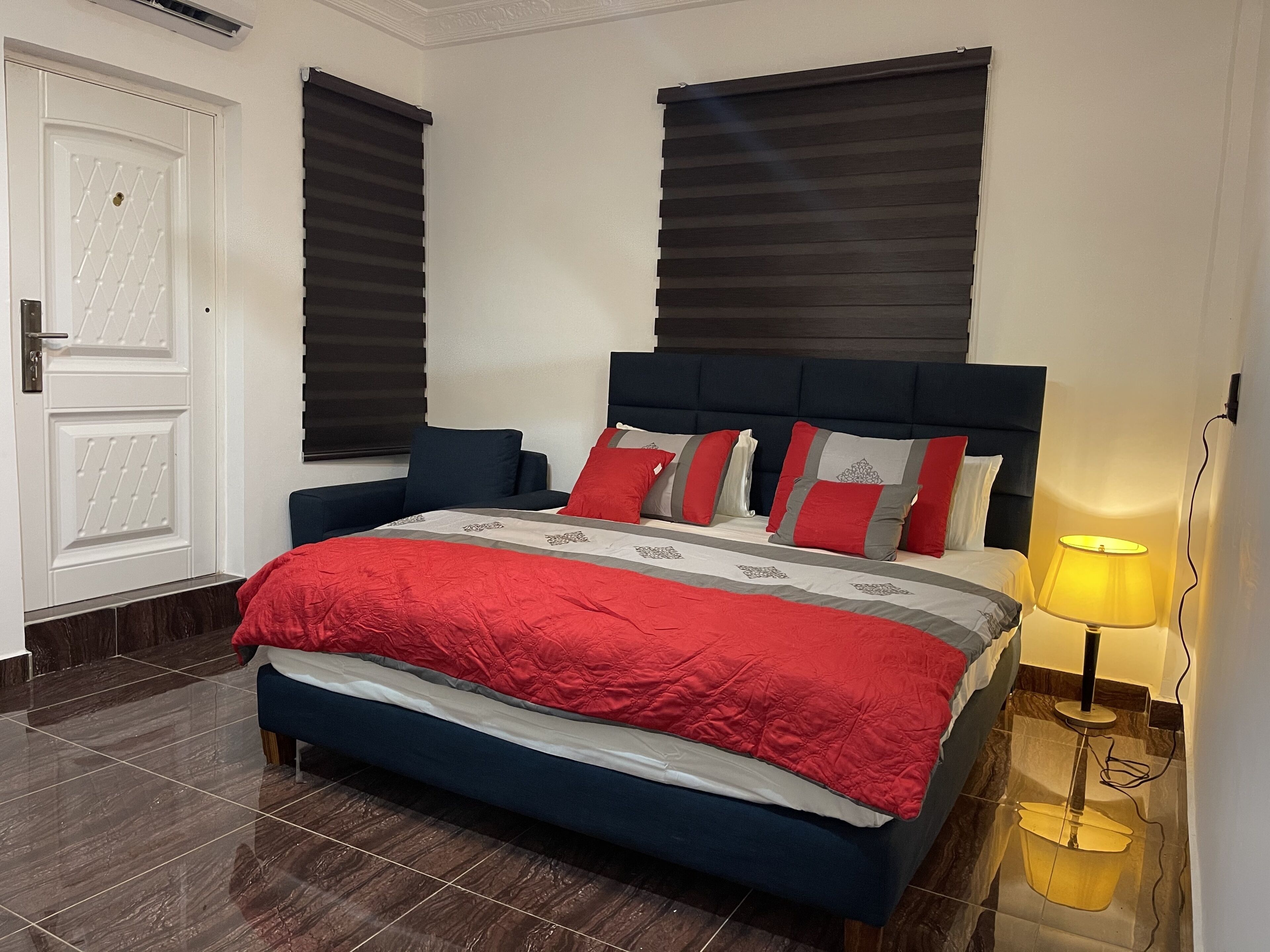 A neatly arranged bedroom with a bed, a bedside lamp, and a door.