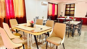 Un espace repas doté d’un sol carrelé en marbre, d’une table centrale entourée de chaises et d’un buffet installé au fond de la pièce.