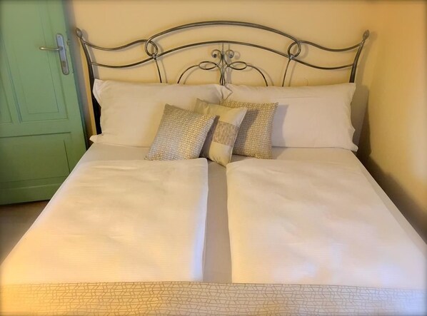 A bed with a metal headboard, two pillows, and a plain wall.