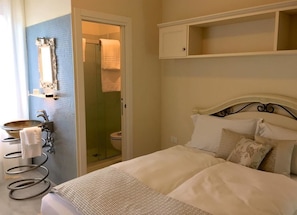 Una habitación de hotel con una cama, un baño con ducha, lavamanos y espejo.