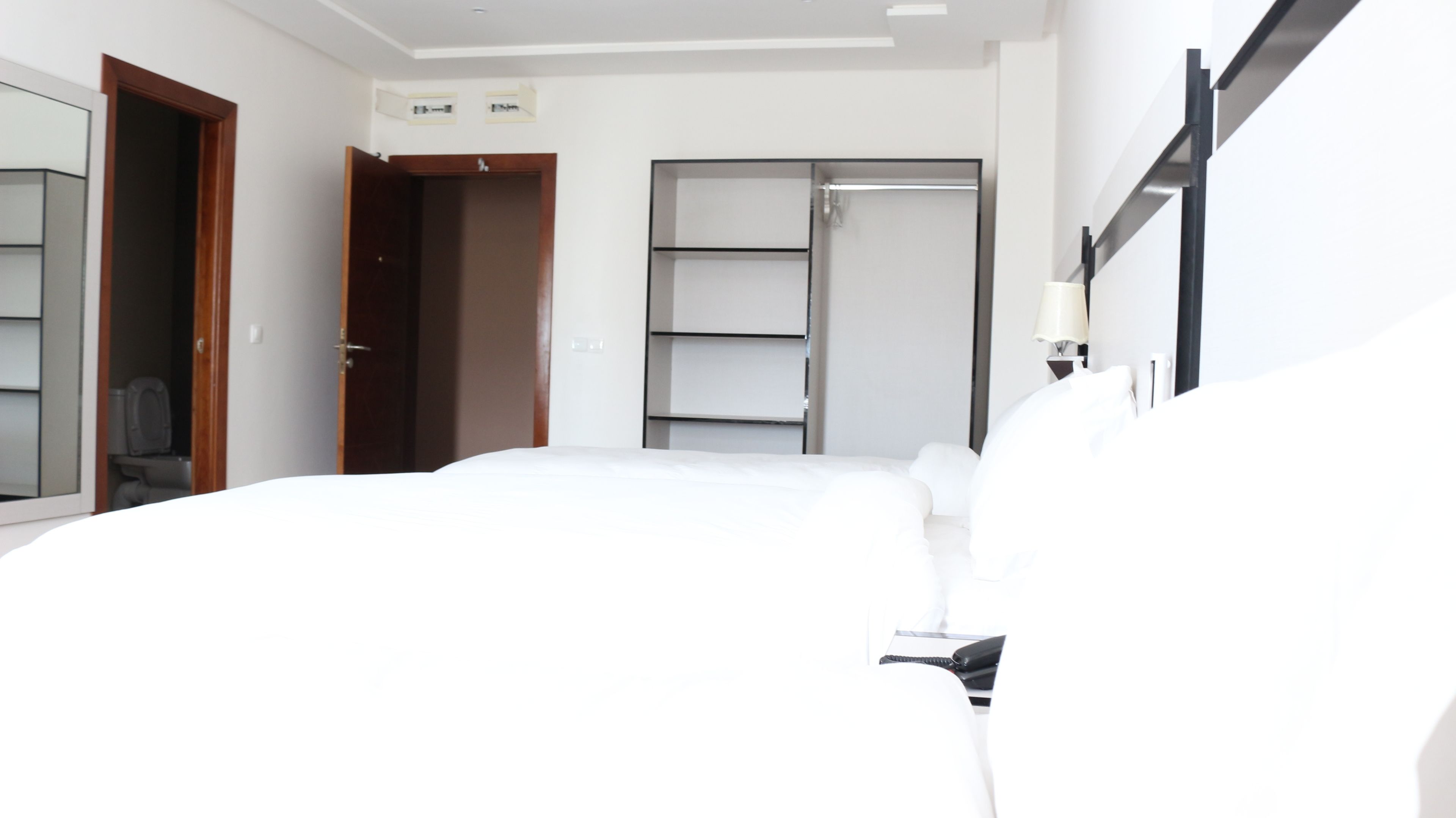 A hotel room with a bed, a wardrobe, and a mirror.