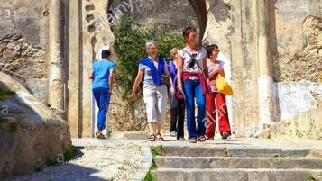Un arco de piedra que conduce a la entrada de un castillo, con turistas subiendo las escaleras.