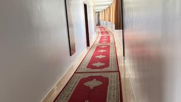 A long, narrow hallway with a red carpet and beige walls.