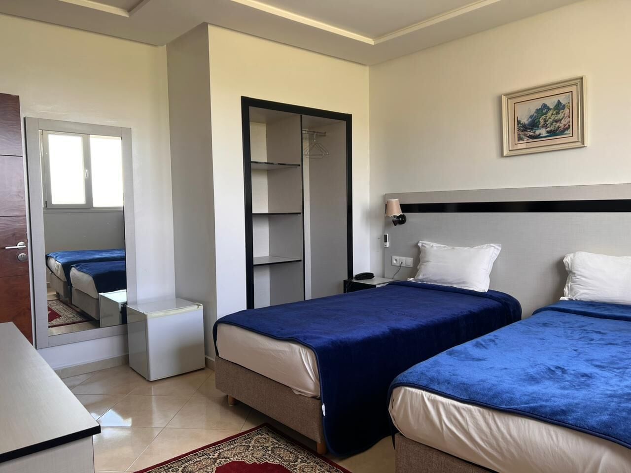Habitació d'hotel amb dos llits, un armari, un escriptori i un mirall.