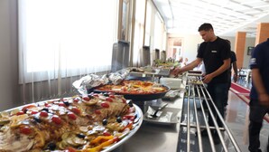 A buffet setup with various dishes, including a large platter of roasted chicken and vegetables, and a pizza. - Hotel Tanger Med (Melloussa)