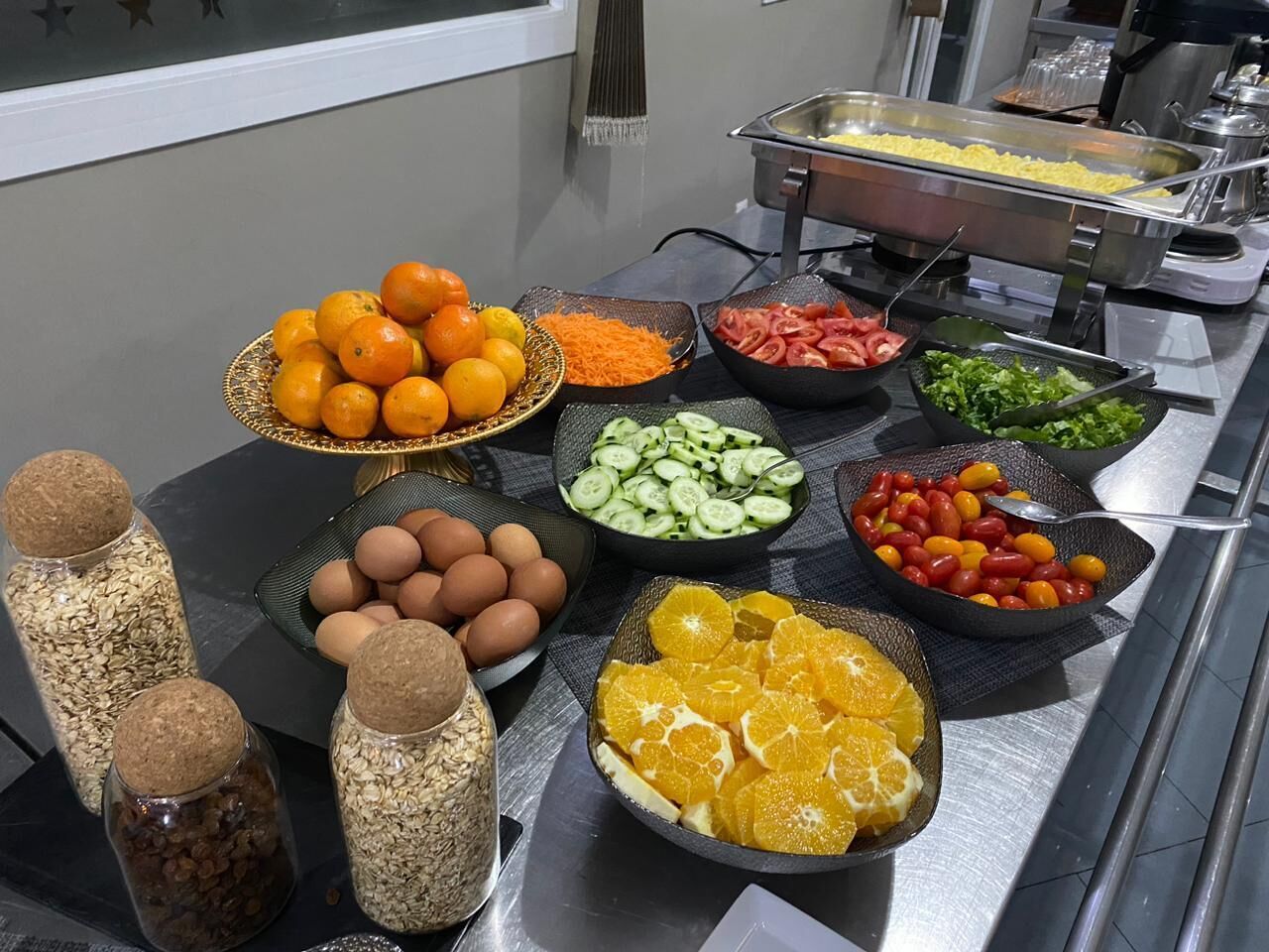 Una mesa de buffet con diversos alimentos, incluyendo naranjas, pepinos, huevos y otras verduras.