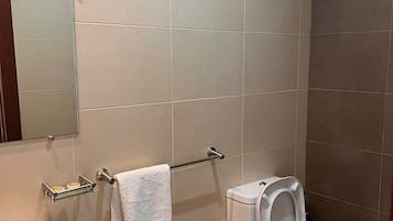Et badeværelse med toilet, håndvask og håndklædestang.
