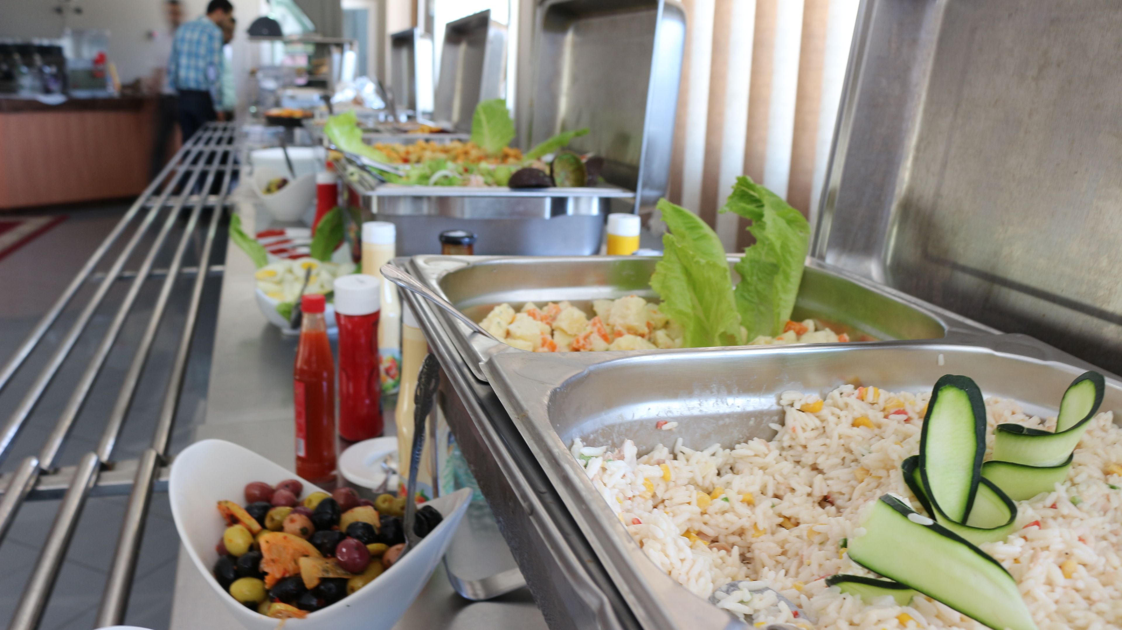 Un buffet con diverse pietanze, tra cui riso, verdure e un'insalata.