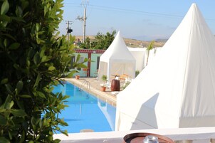 Una piscina al aire libre, sombrillas, sillones reclinables de piscina