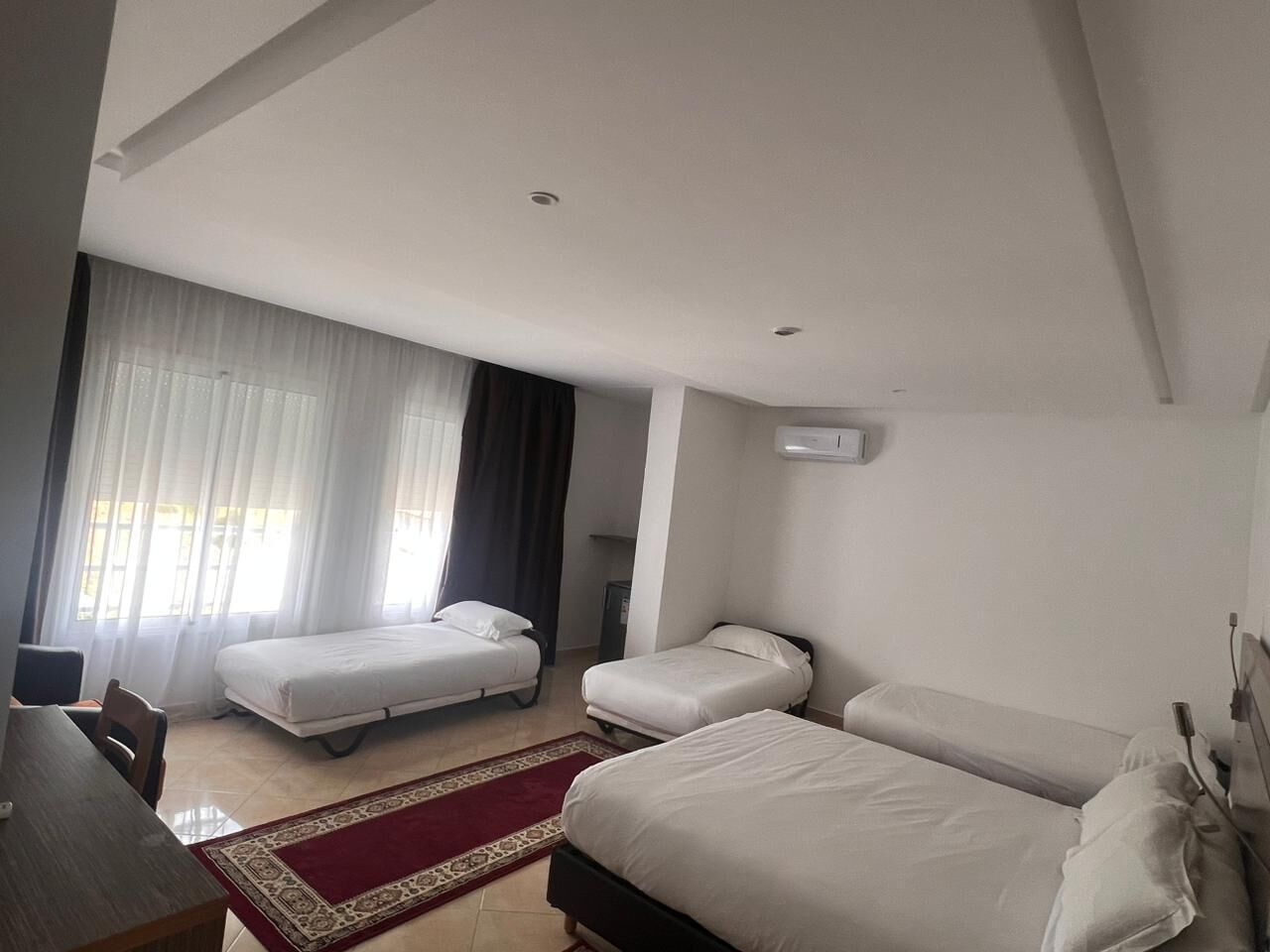 A hotel room with two single beds, a desk, and a chair.