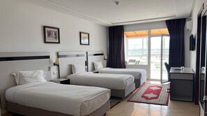 A hotel room with two beds, a desk, a chair, a TV, and a large window with curtains. - Hotel Tanger Med (Melloussa)