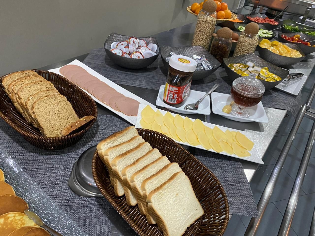 Une table de buffet proposant divers aliments, notamment du pain, du fromage et des condiments.