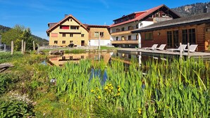 A hotel with a pool, surrounded by lush greenery and a clear blue sky.