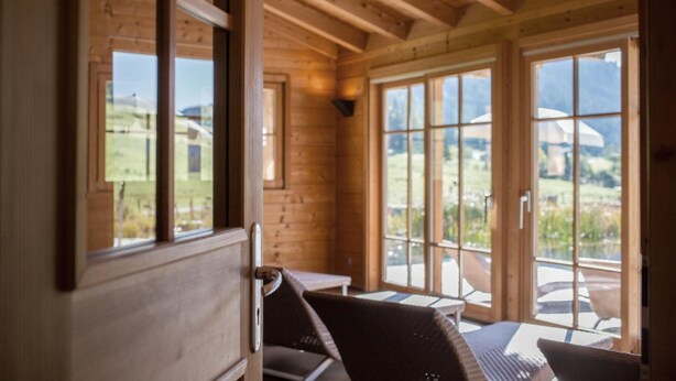 A wooden cabin with large windows and a view of the outdoors.