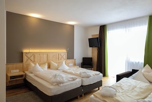 Une chambre d’hôtel avec deux lits, une télévision, une chaise et une fenêtre avec des rideaux.