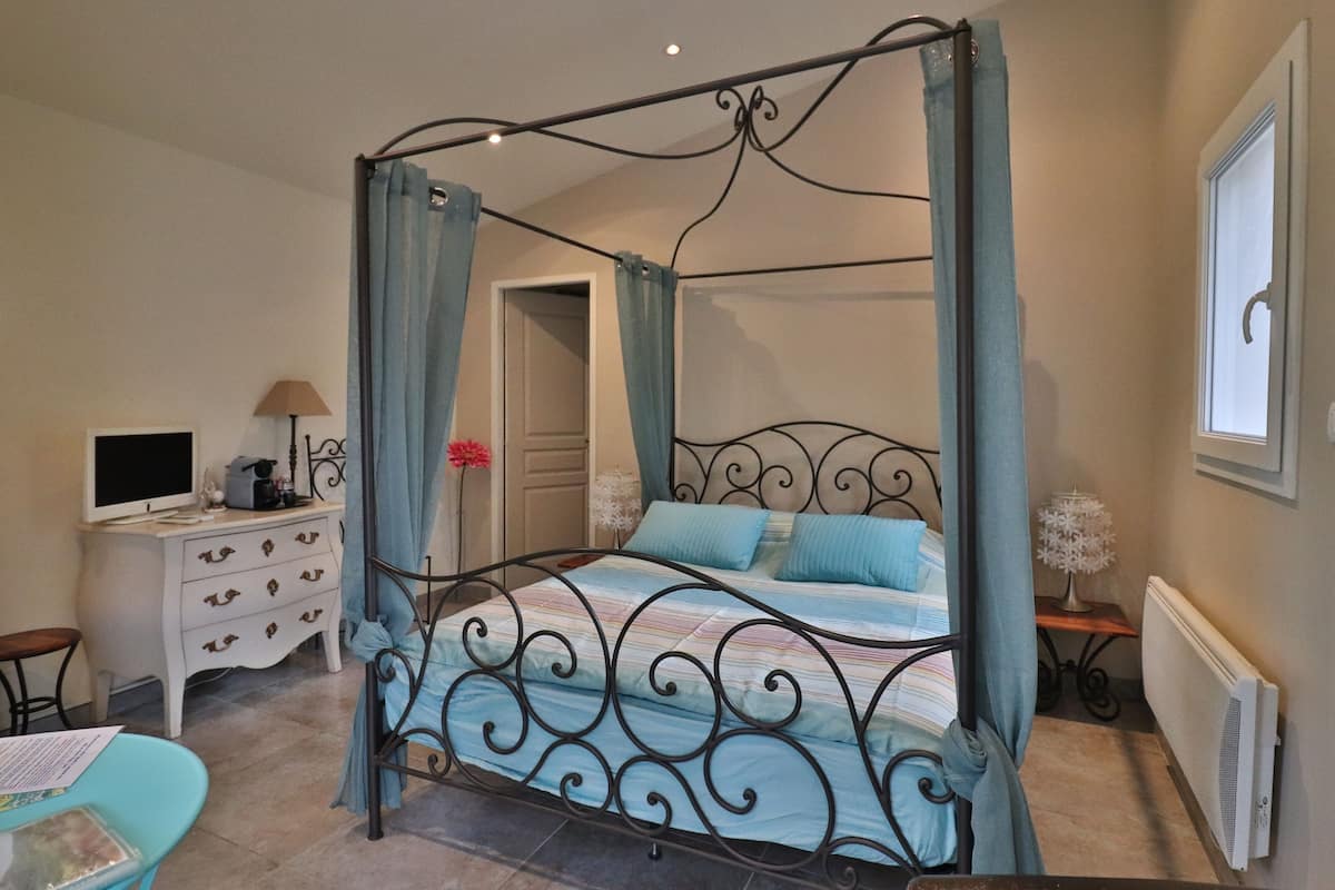 A four-poster bed with a canopy, a desk with a computer, and a chair.