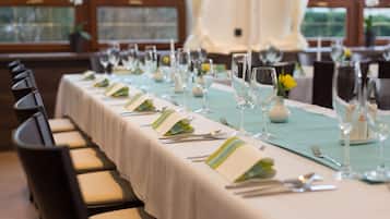 Una larga mesa de comedor dispuesta con sillas, copas y un mantel de color claro.