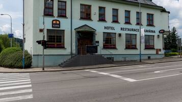 A two-story building with a sign reading "HOTEL RESTAURANCE" and "CAVÁRNÁ" on the facade.