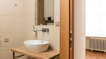 Un baño moderno con tocador de madera, un lavamanos blanco y un espejo.