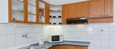 A kitchen with wooden cabinets, a microwave, and a sink.