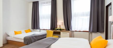 A hotel room with two beds, a desk, and a chair.
