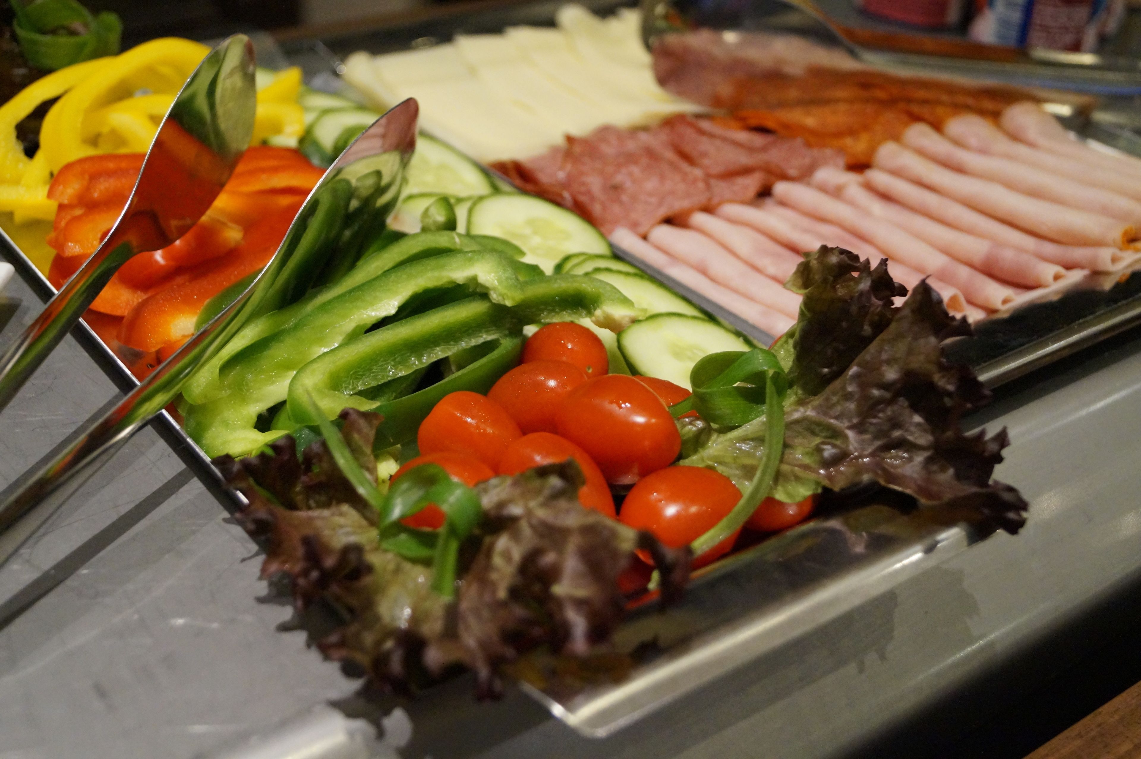 Un buffet proposant une variété d’aliments, notamment des légumes coupés en tranches, du fromage et de la charcuterie.