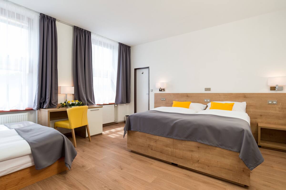 A hotel room with two beds, a desk, and a chair.