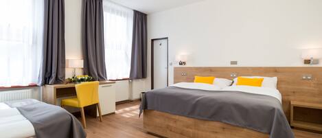 A hotel room with two beds, a desk, and a chair.