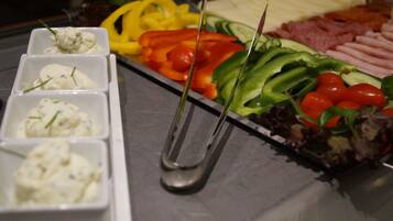 Ein reichhaltiges Buffet mit verschiedenen Speisen, darunter Käse, Gemüse und Fleisch.