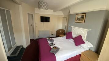 Ein Hotelzimmer mit Bett, Sessel, Fernseher und Heizkörper.