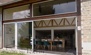 Un restaurante con entrada de vidrio grande, vigas de madera y pared de piedra.