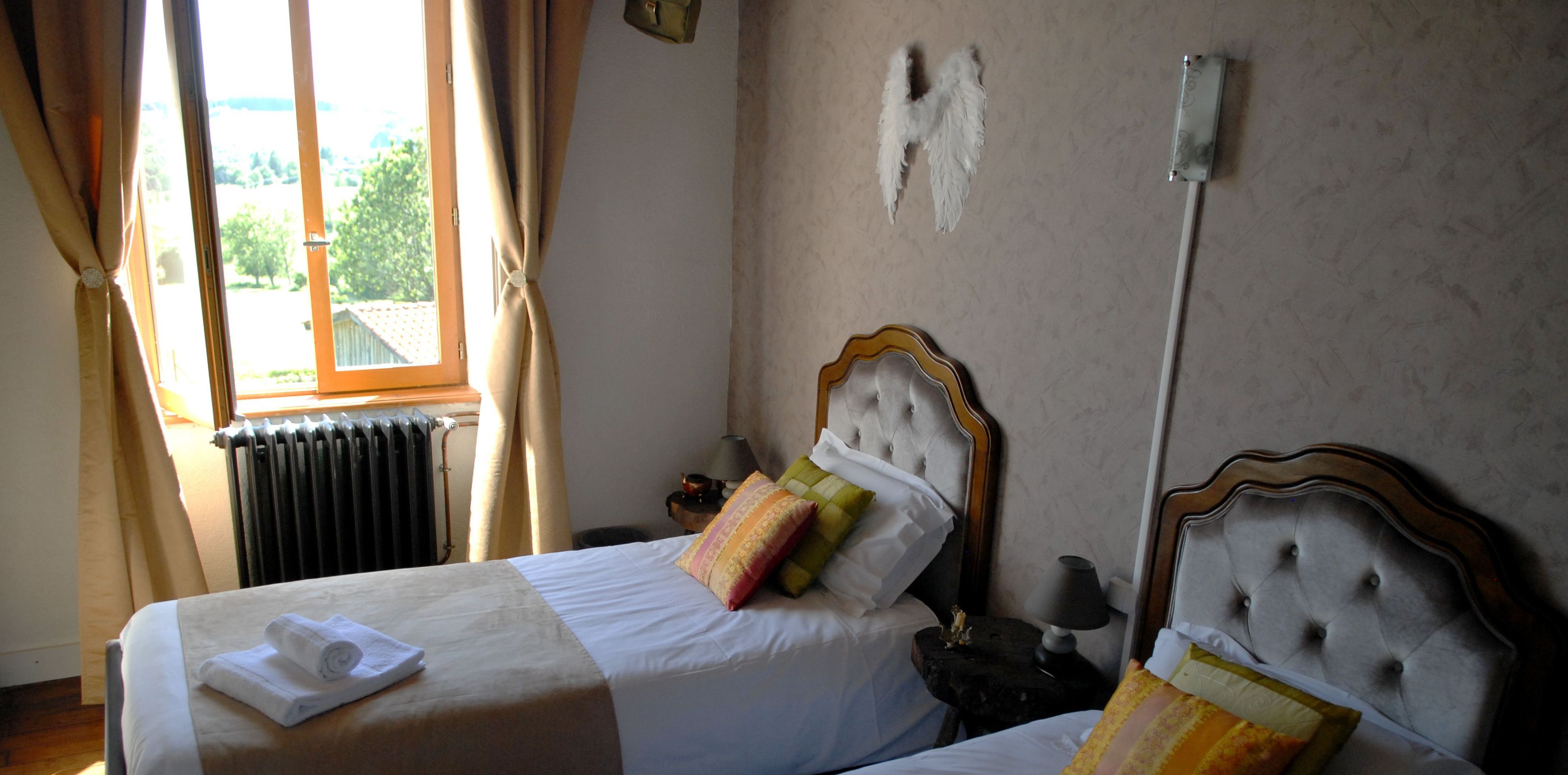 Habitación de hotel con cama, mesita de noche, lámpara y ventana con cortinas.