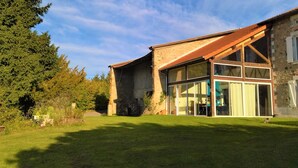 A modern house with a stone facade, large glass windows, and a sloped roof.