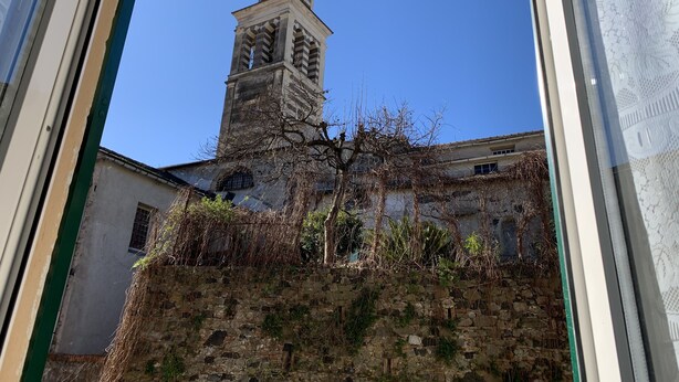A view of a historic building with a tall tower and a stone wall. - Appartamenti St'Andrea (Levanto)