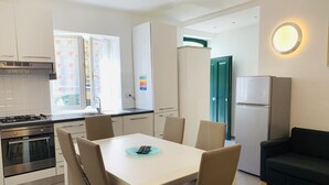 A modern kitchen with a dining table, chairs, a stove, and a refrigerator. - Appartamenti St'Andrea (Levanto)