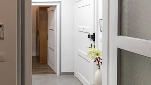 A hallway with white doors, a wooden bench, and a vase with flowers. - Bacu Apartments Zagreb (Zagreb)
