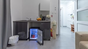A compact kitchen with a refrigerator, sink, and a small countertop with fruits and a kettle. - Bacu Apartments Zagreb (Zagreb)