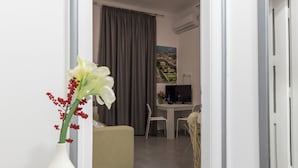 A modern hotel room with a wooden desk, a comfortable sofa, and a view of a cityscape through the window. - Bacu Apartments Zagreb (Zagreb)